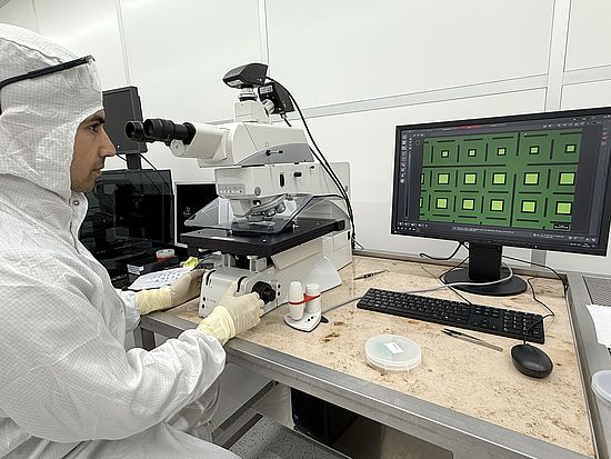 Eine Person kontrolliert einen Wafer am Mikroskop